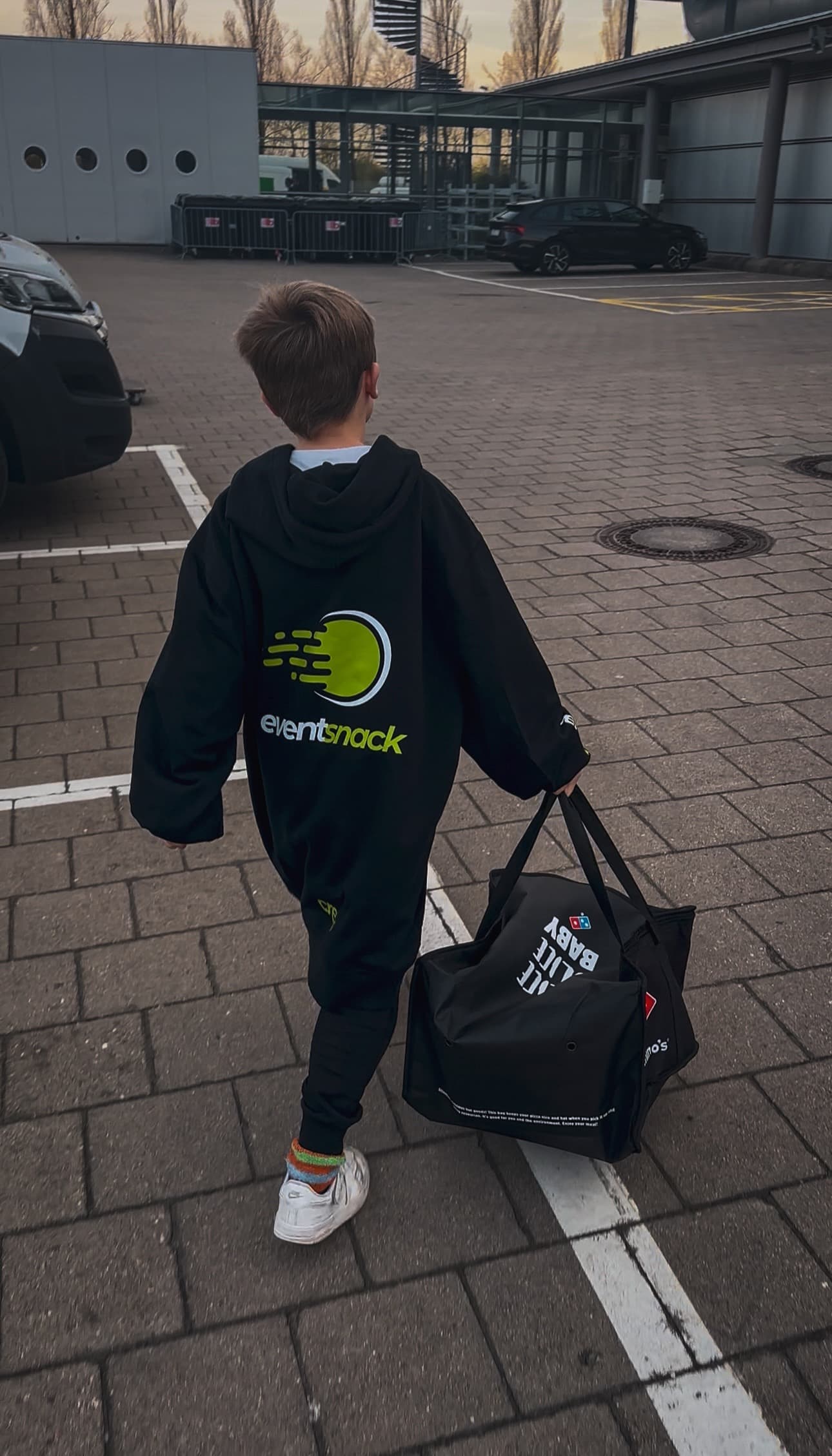 EventSnack-Runner mit Domino’s-Pizzabag auf dem Weg zur Gaming-Fläche